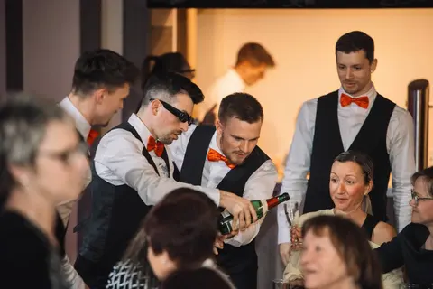 Showkellner schenken Champagner am Tisch einer Gästegruppe aus.