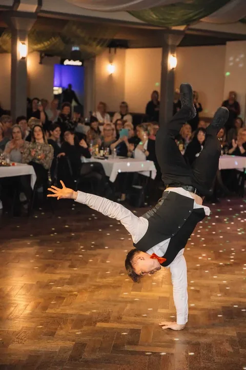 Ein Showkellner balanciert auf einer Hand vor den Gästen.